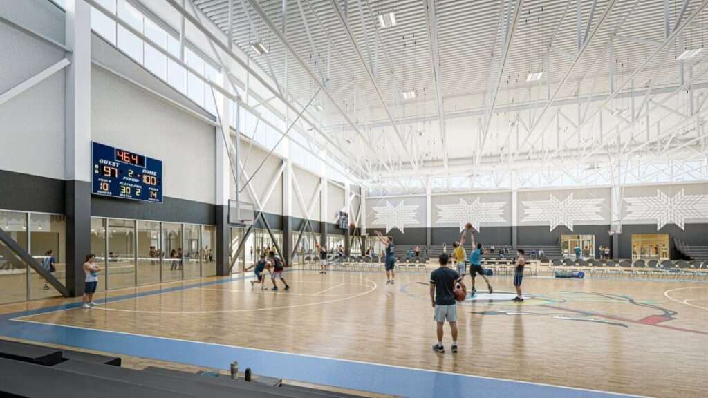 Large indoor basketball court featuring high ceilings, steel trusses, clerestory windows, and wall patterns.