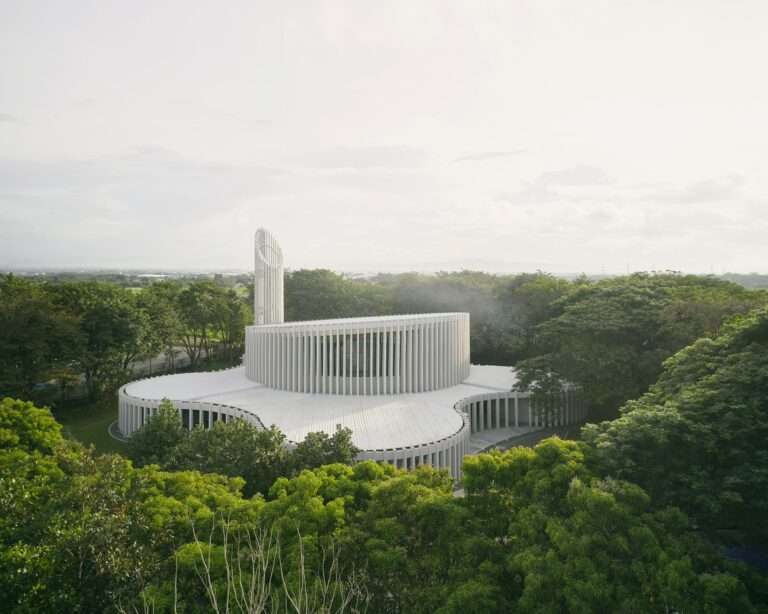 Aerial view of Santuario de La Salle by CAZA featuring white parametric concrete fins and interconnected circular volumes surrounded by lush trees in Biñan, Philippines.
