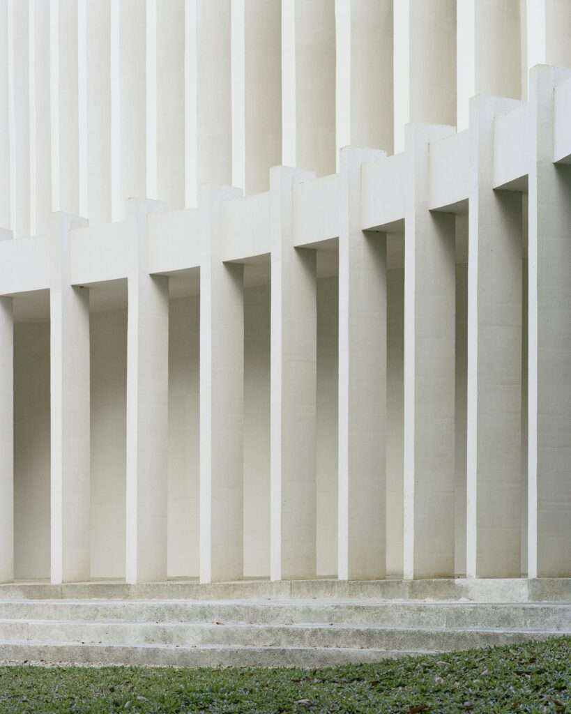 Close-up architectural detail of textured white concrete vertical columns forming a shaded colonnade at Santuario de La Salle.