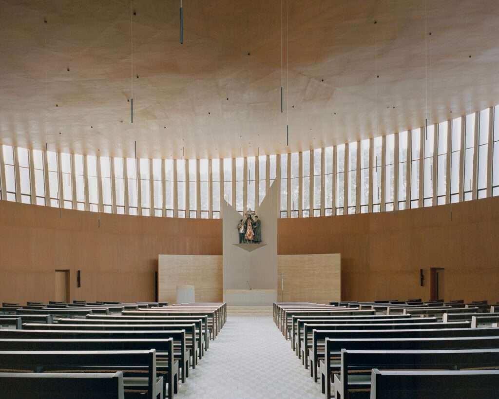 Central altar view of Santuario de La Salle featuring wooden pews facing a central sculpture under an expansive wooden ceiling illuminated by high clerestory windows.