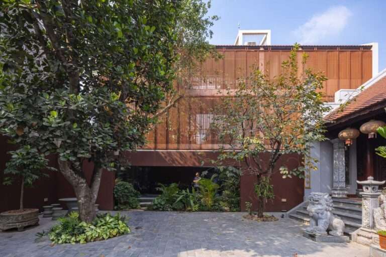 Courtyard of NB01 House showing a traditional Vietnamese altar house juxtaposed with a modern residential block featuring a timber steel screen facade.