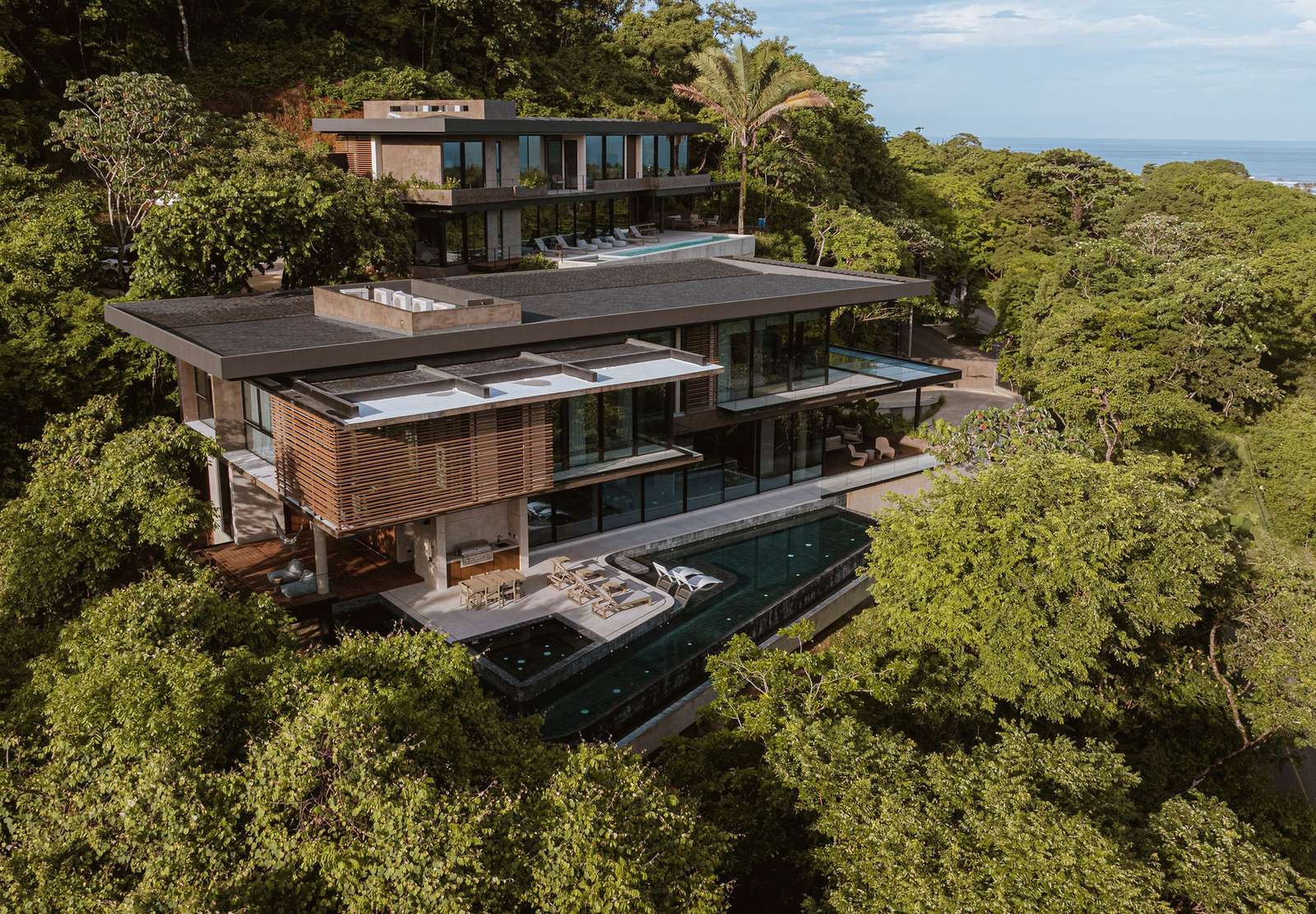 Aerial view of KUL Nosara luxury hillside villas surrounded by dense tropical rainforest and overlooking the ocean.
