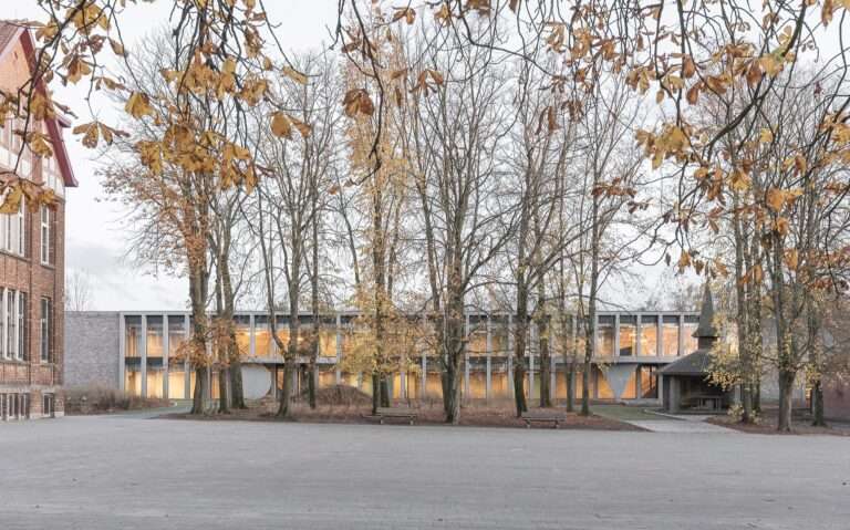 Cardinal Mercier College new building modern glass and brick facade viewed from the tree-lined campus courtyard.