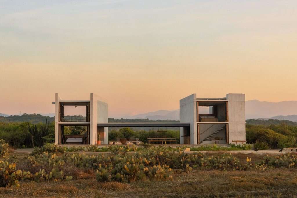 Front elevation of Casa Macahuite showing two concrete modules connected by a central shaded wooden deck facing a desert landscape.