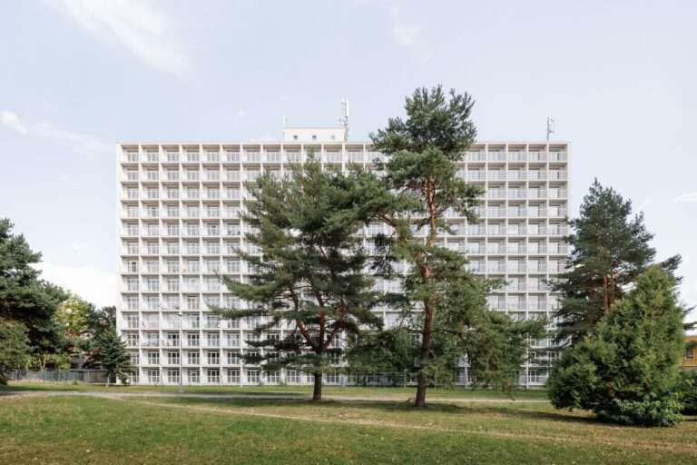Prefabricated concrete facade of the 13-story Terasa housing complex in Kosice with modular balconies and surrounding green trees.
