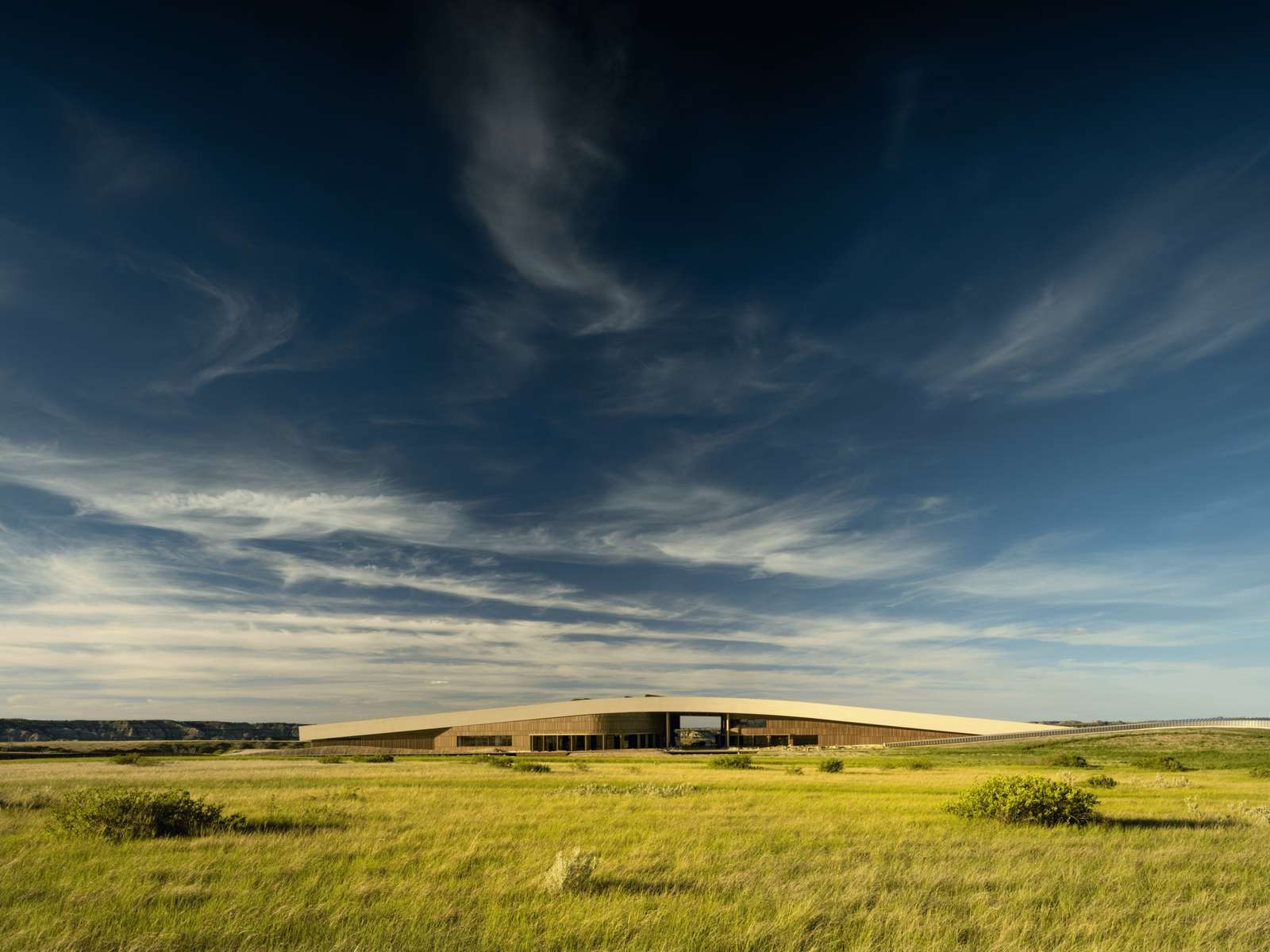 The Theodore Roosevelt Presidential Library building integrated into the North Dakota Badlands landscape under a blue sky.