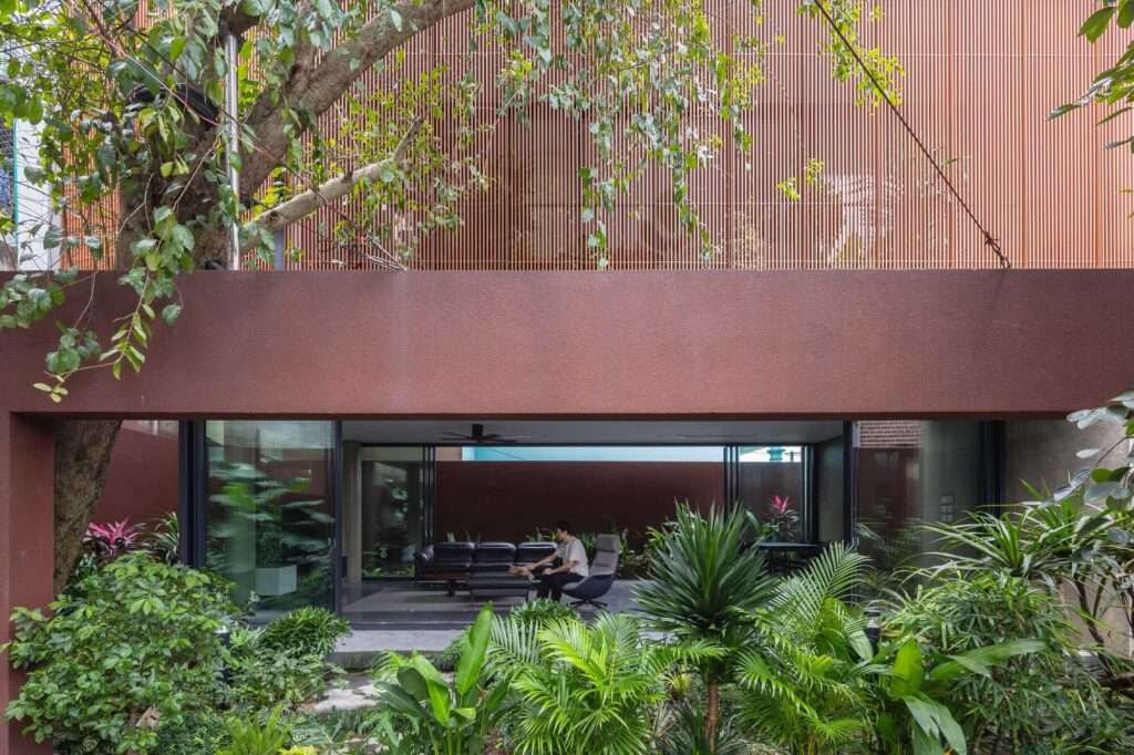 Modern minimalist living room of NB01 House opening directly onto a lush green garden through large sliding glass doors.