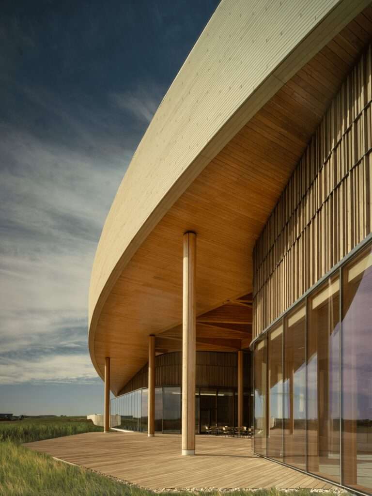 Close-up of the library's large timber-clad exterior canopy and glass facade overlooking the prairie.