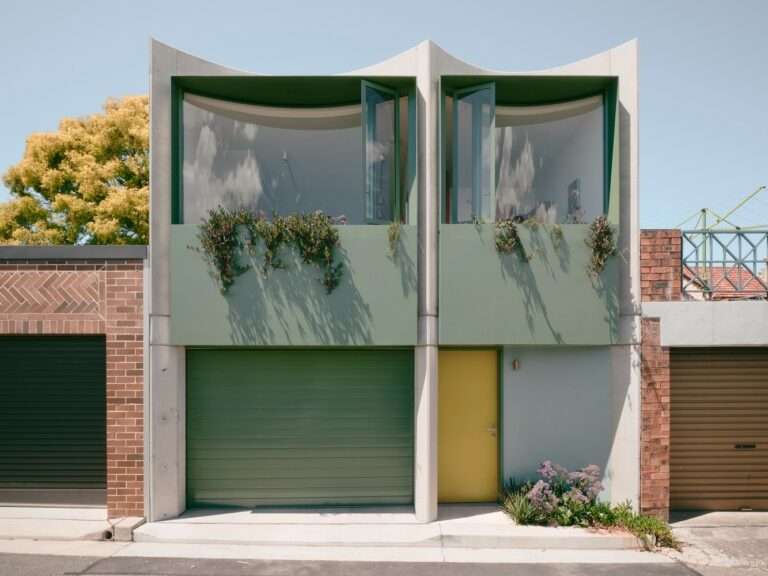 Symmetrical modern two-story laneway house in Sydney with green window frames, curved glass windows, concrete framing, integrated green planters, and a yellow entry door.