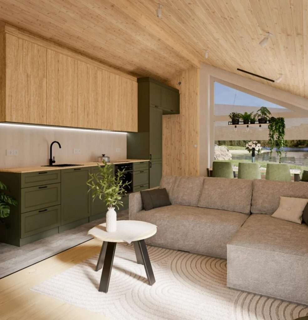 Interior view of the Evergreen XL, looking from the lounge with a grey L-shaped sofa toward a fully equipped olive green kitchen and dining table with green chairs, all under a vaulted wooden ceiling.