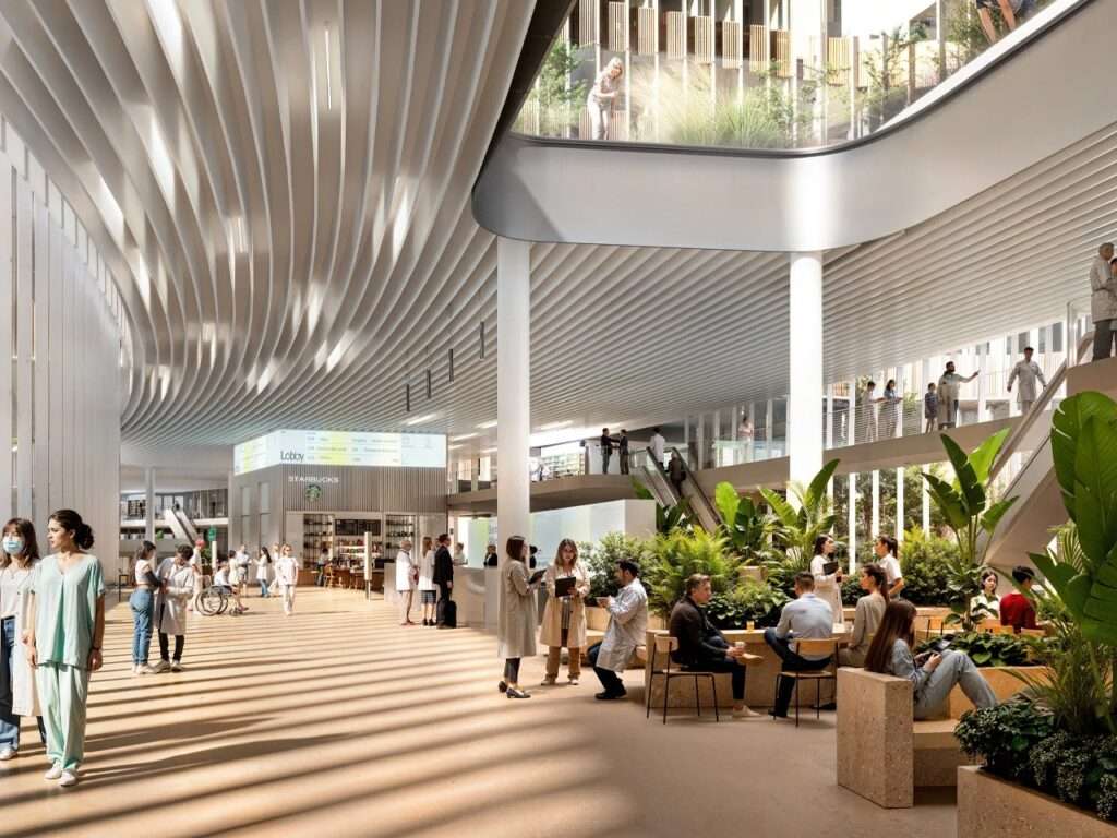 High-ceilinged glass atrium inside Brescia hospital with natural sunlight patterns on the floor, modern cafes, and indoor tropical plants.