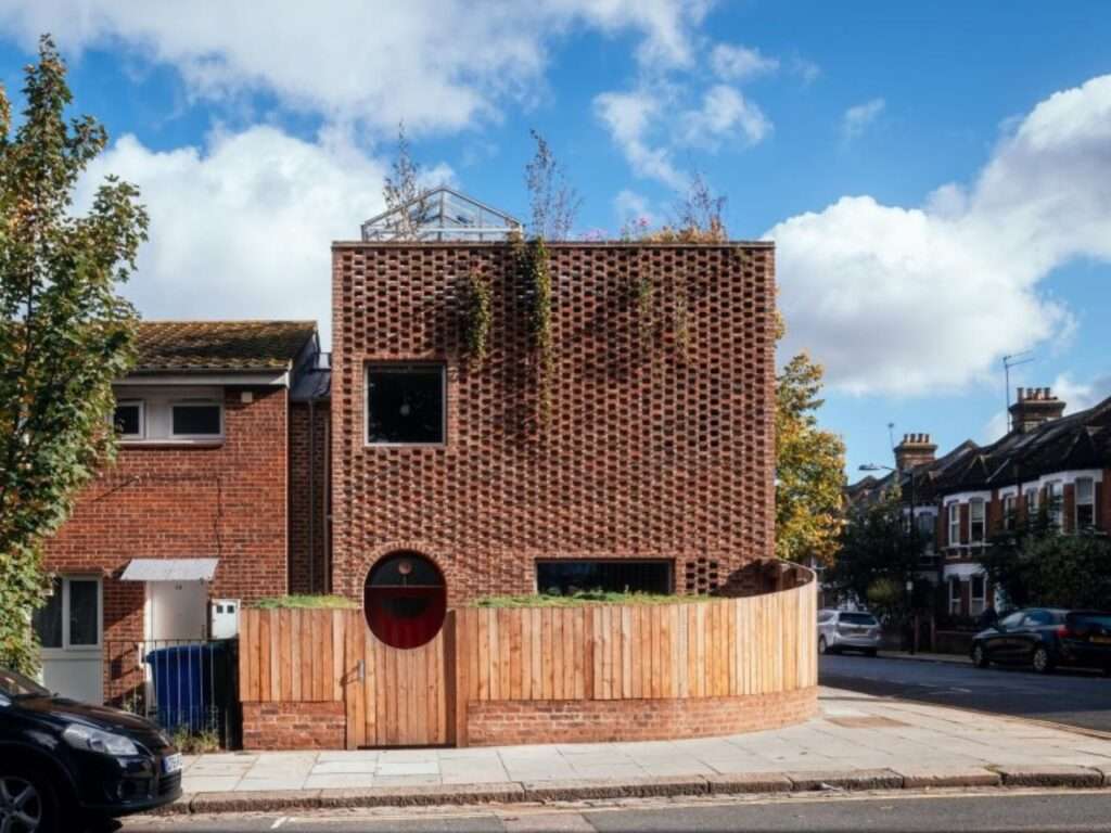 Exterior front facade of Peckham House featuring hit-and-miss brickwork, an arched timber entrance gate, and a rooftop garden.