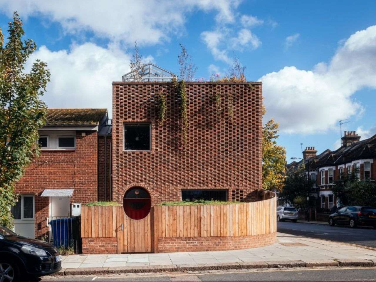 Exterior front facade of Peckham House featuring hit-and-miss brickwork, an arched timber entrance gate, and a rooftop garden.