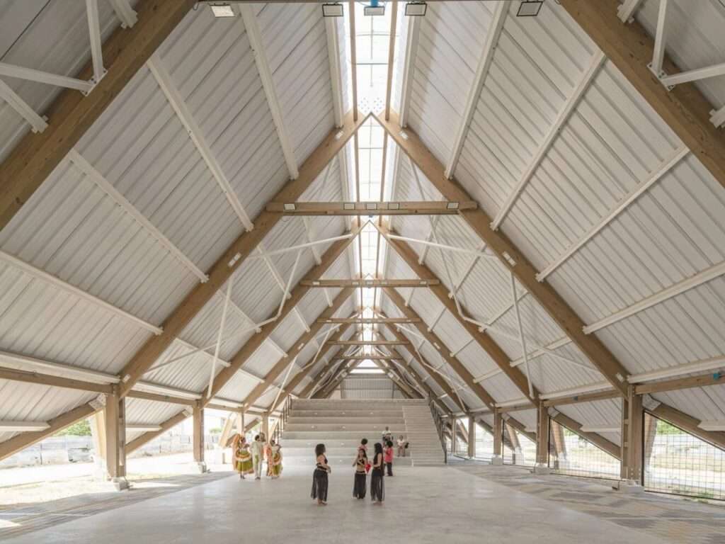 Interior of the cultural center showing the massive timber A-frame roof trusses and central longitudinal skylight.