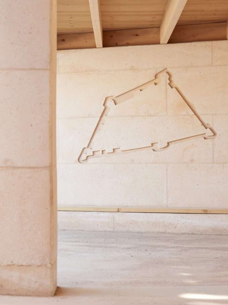 Close-up of an architectural engraving detailing the historic ramparts of Porto-Vecchio on a bush-hammered concrete wall with local white limestone aggregate.