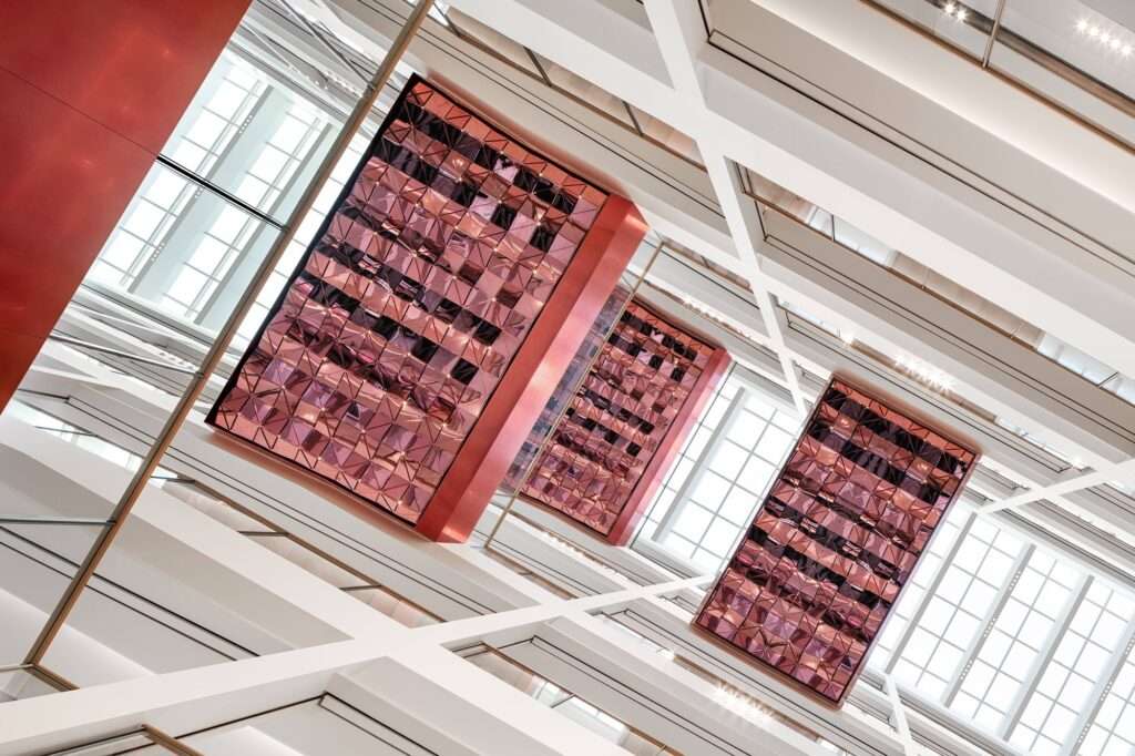 Direct look-up view of the multi-layered interior ceiling grids and pink-tinted reflective geometric panels at Wuxi MixC Mall.