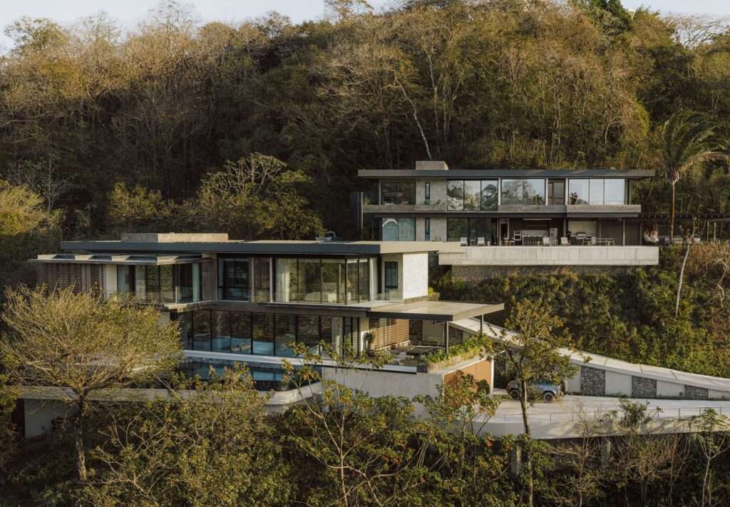 Exterior front view of two terraced concrete and glass villas built into a steep forested hill at KUL Nosara.