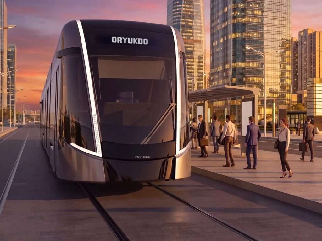 Close-up front view of the Oryukdo tram at a station platform during sunset, with golden hour sunlight reflecting off the surrounding corporate towers.