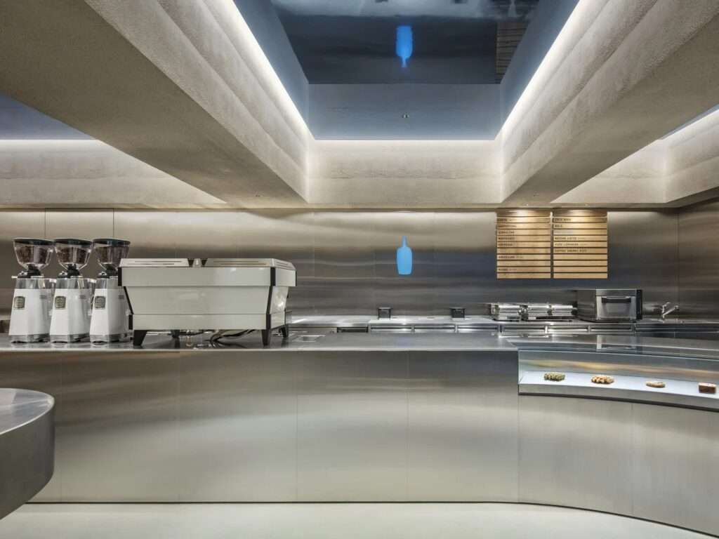 Elevation view of the stainless steel coffee bar with coffee grinders, espresso machine, and menu board at Blue Bottle Coffee Harajuku.