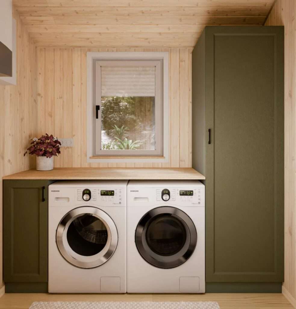 A dedicated utility room interior with a Samsung washing machine and a separate Samsung dryer side-by-side under a wooden countertop, next to an olive green utility closet and a window.