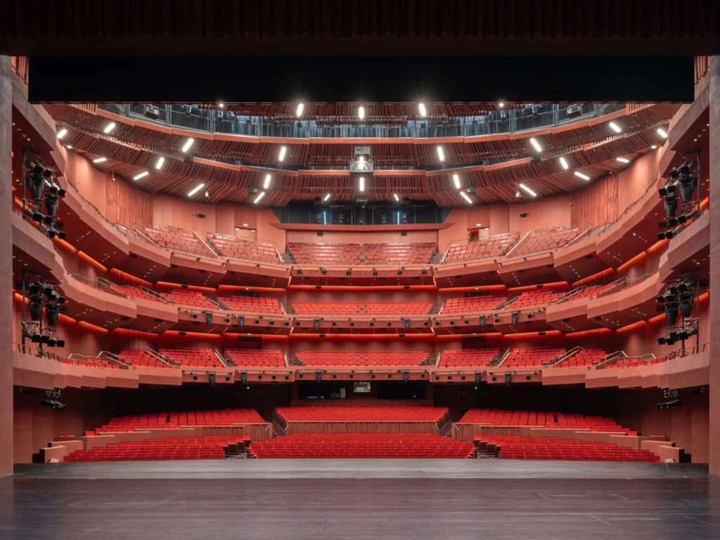 Interior view of a vibrant red theater hall inside the Shanghai Grand Opera House featuring tiered seating.