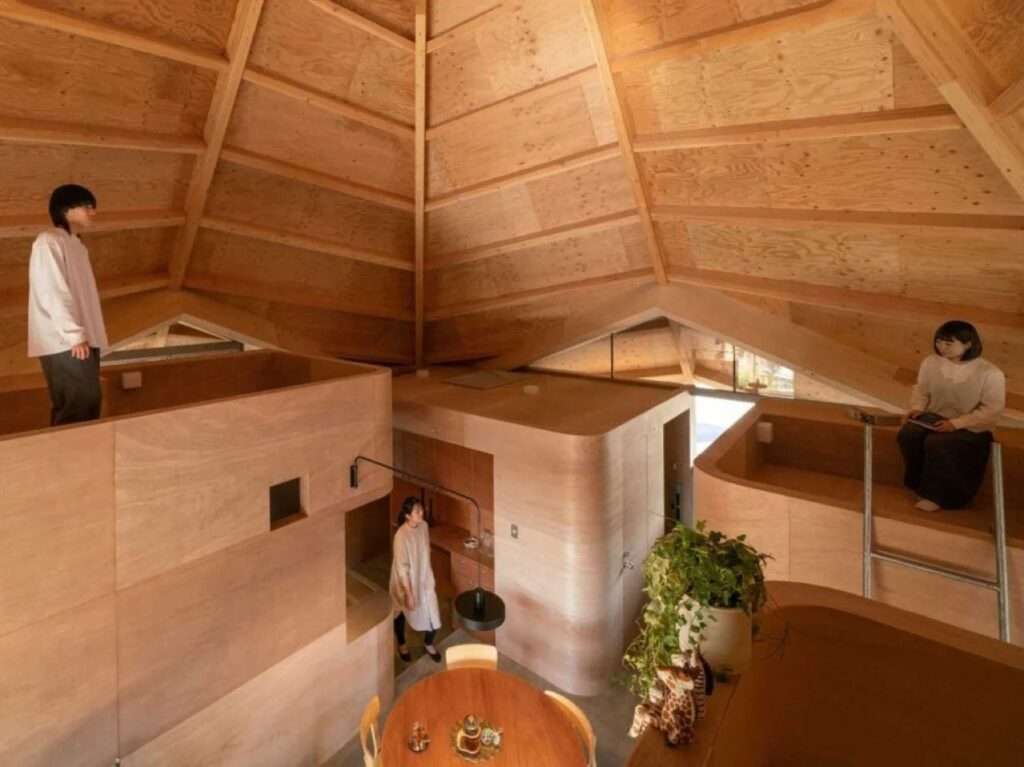 Multi-level view inside a timber home featuring residents occupying different elevated spaces and a round dining table below.