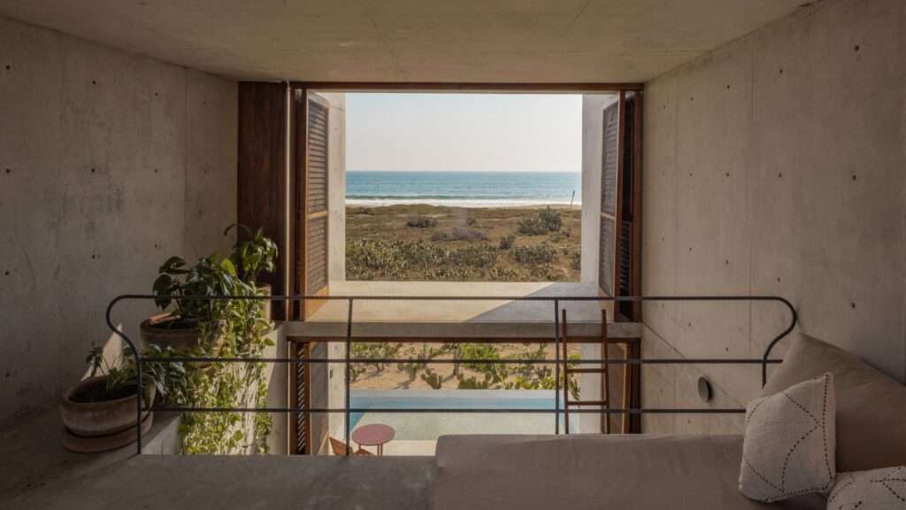 Upper-floor interior room with wooden louvered shutters opening up to direct views of the ocean horizon.