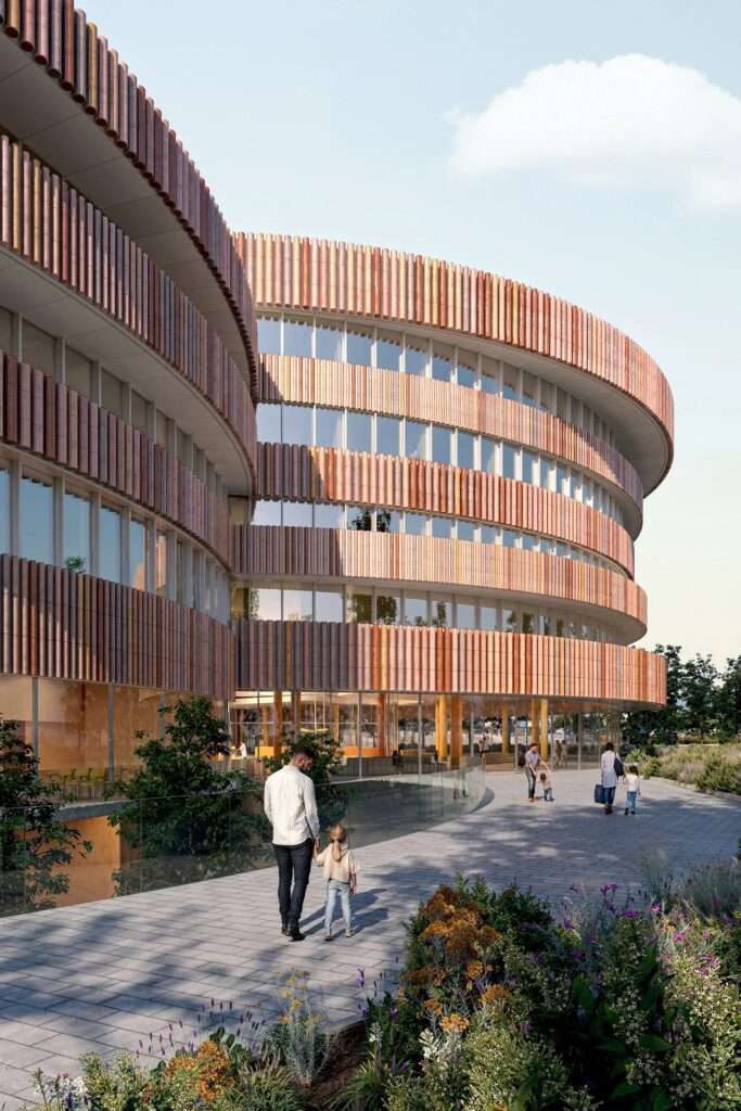 Exterior view of the cylindrical children's hospital building clad in earth-toned vertical terracotta slats with families walking on a stone pathway.