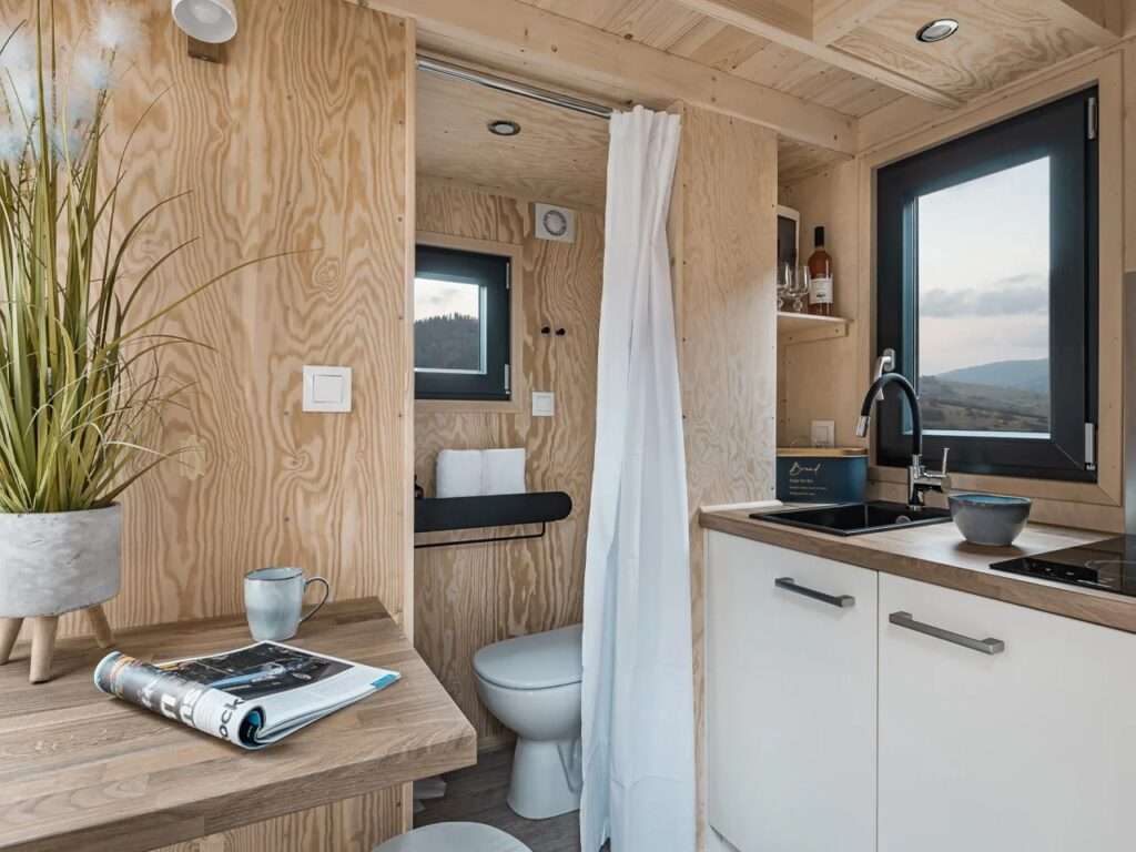 Compact interior layout of La Ruche showing a kitchen counter next to a toilet partitioned by a soft white curtain.