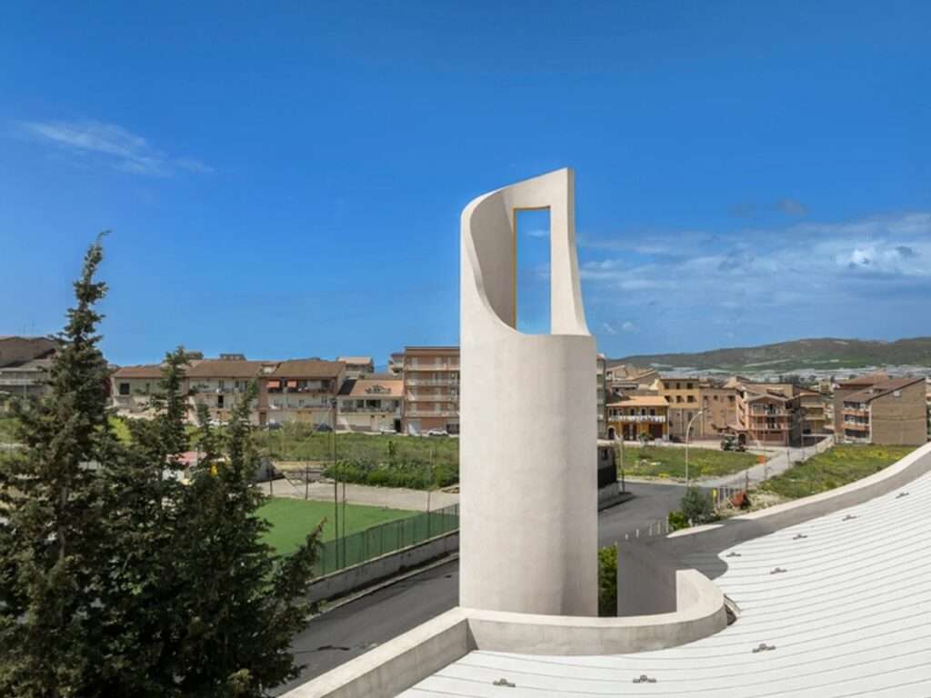 View from the roof of Santa Barbara Parish showing the undulating white roofline and the minimalist, open-slat cylindrical bell tower overlooking Licata.