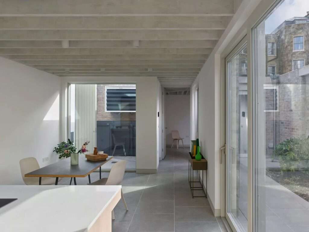 Interior corridor view of a single-story home showing gray floor tiles, white walls, and views leading toward the central courtyard.