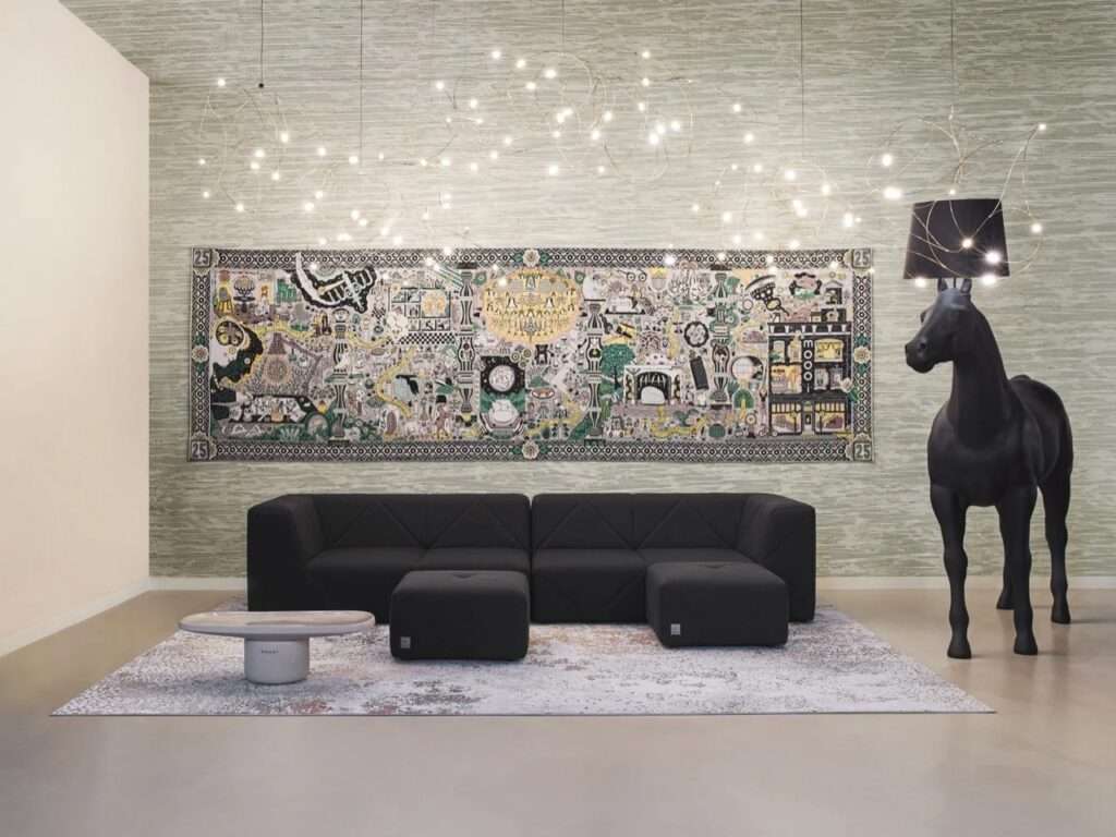 Contemporary living room with a low black modular sectional sofa, an intricate illustrated wall tapestry, and a life-sized black horse statue floor lamp by Moooi.