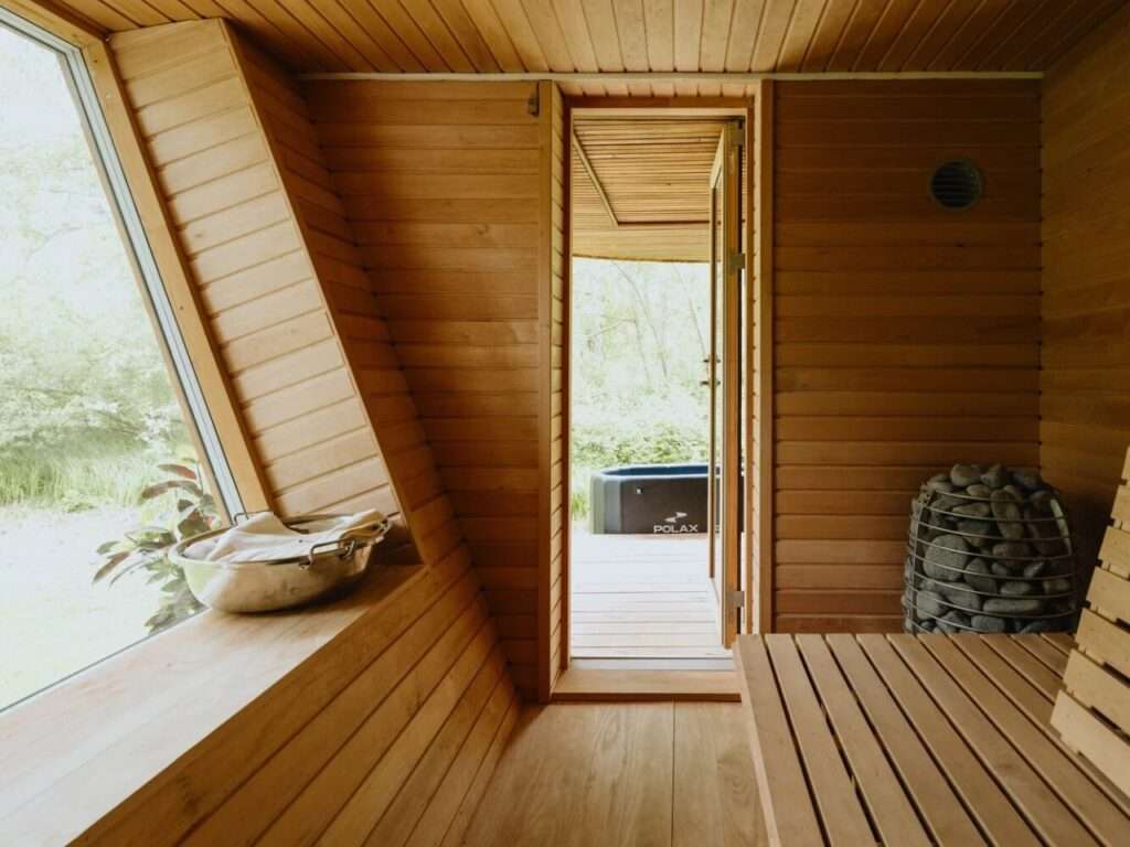 Internal view of EcoNeo integrated wooden sauna room with glass door leading to the outdoor deck.