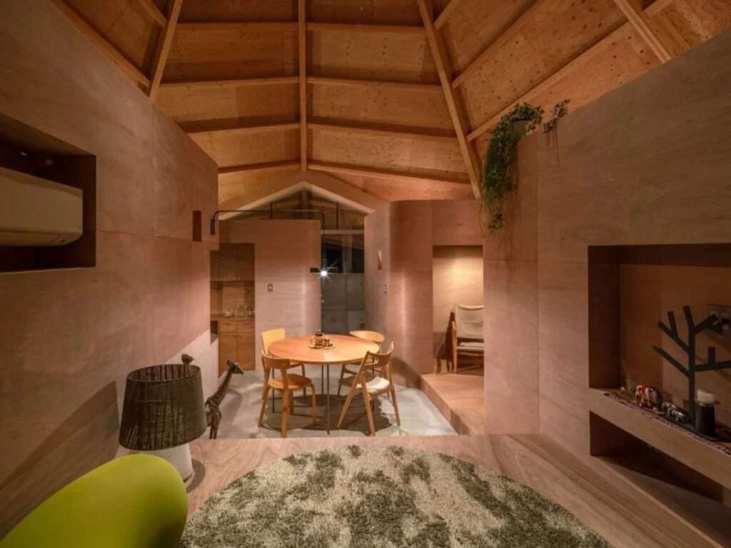 Warmly lit evening view of an open plan residential interior with an organic round rug and a circular dining table.