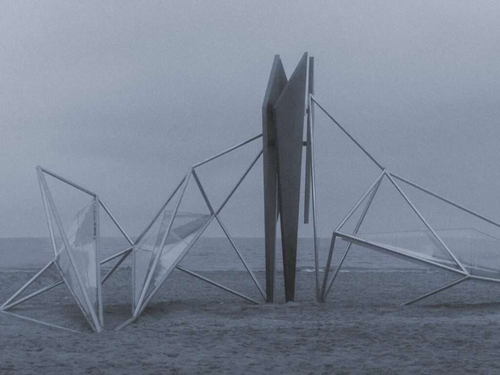 Symmetrical view of the metal installation structure on a gray beach under an overcast sky.
