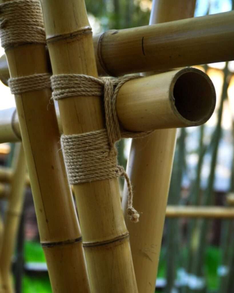 An absolute macro close-up of traditional cross-lashing joinery using organic hemp rope to secure raw bamboo poles together.