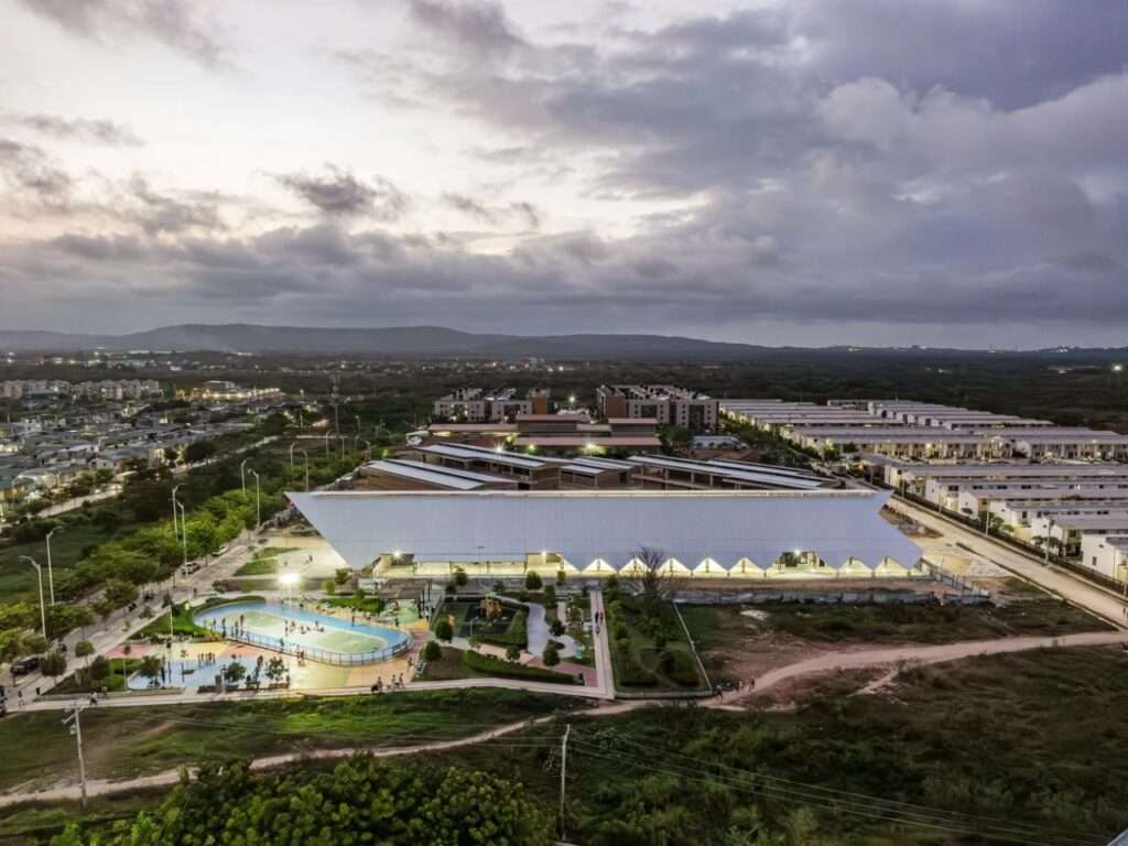 Twilight aerial view of the glowing cultural center structure and the surrounding active public park in Barranquilla.