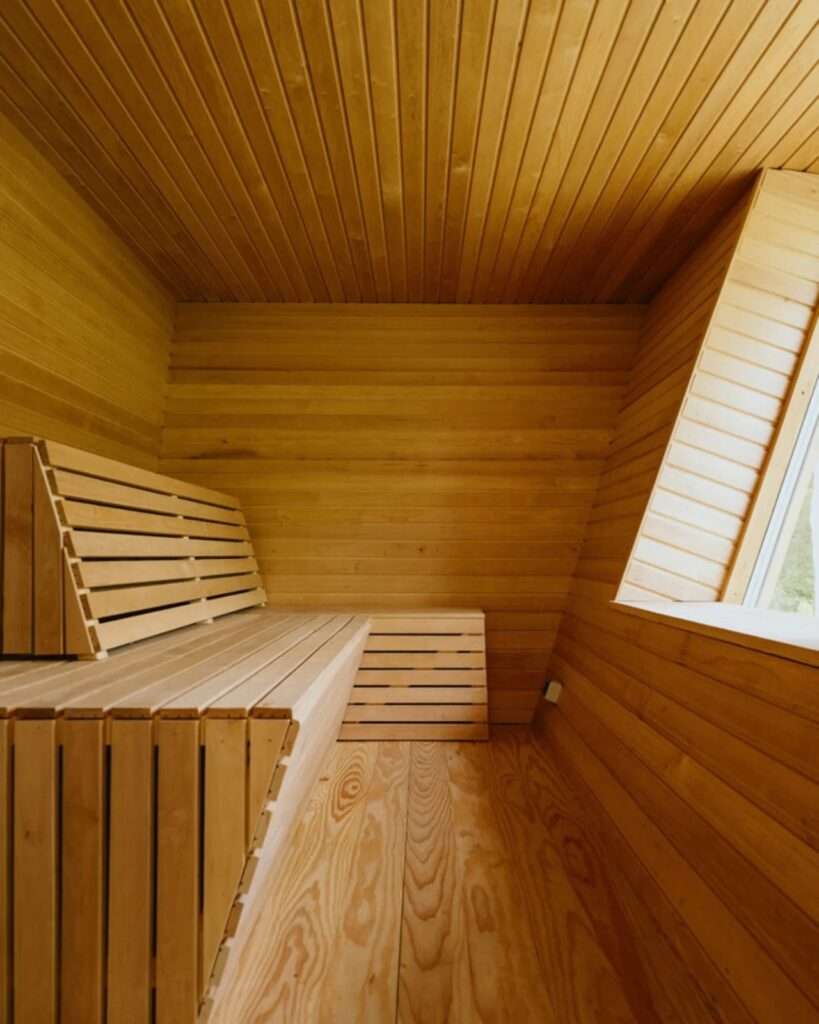 Interior of the all wood slated sauna room inside EcoNeo cabin with angled ceiling window.