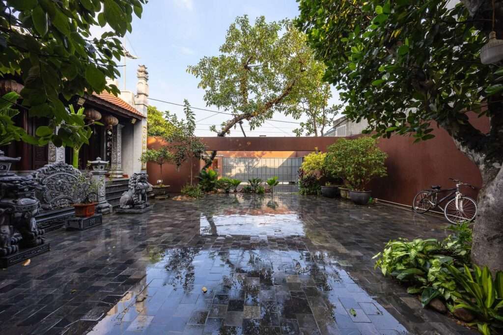 Wet stone pavement reflecting the sky and trees in the inner courtyard of NB01 House after a rain.
