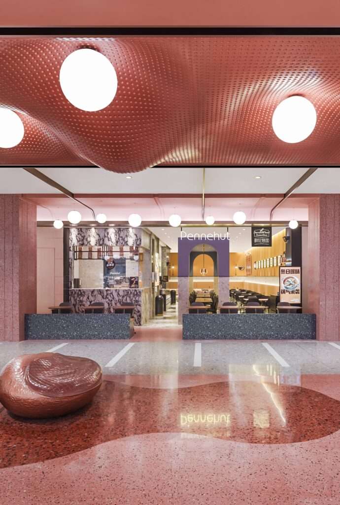 Entrance to the Yummy food court at Wuxi MixC Mall featuring a wavy red perforated ceiling, terrazzo flooring, and integrated circular lighting fixtures.