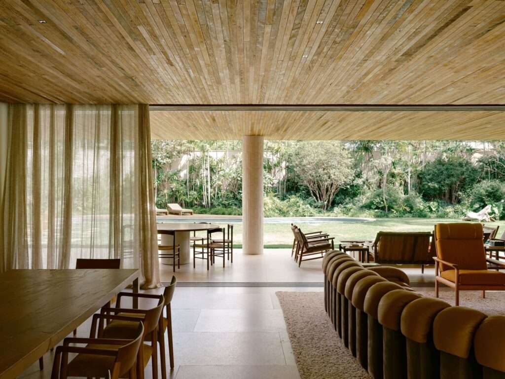 View from the indoor living and dining space looking out to the backyard pool and garden through wide-open sliding glass doors.