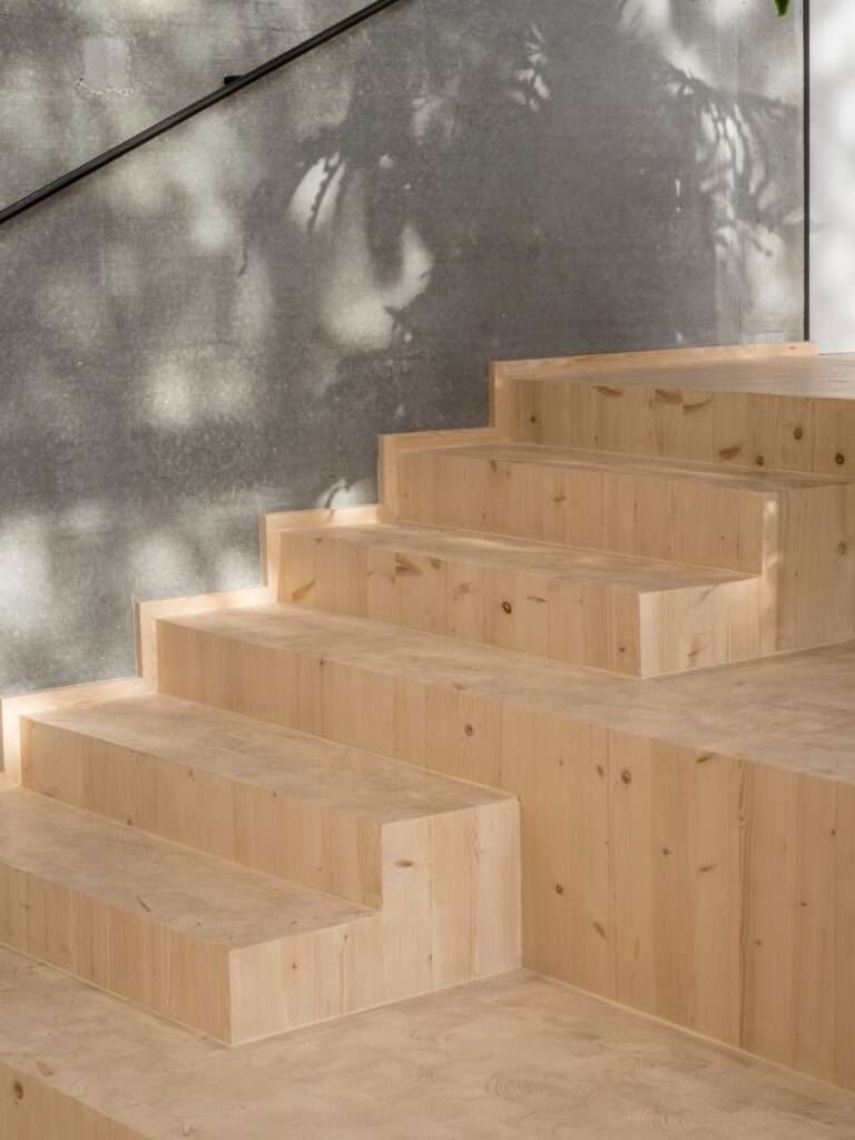 Close-up of minimalist solid timber steps showcasing natural wood grains next to a concrete wall.