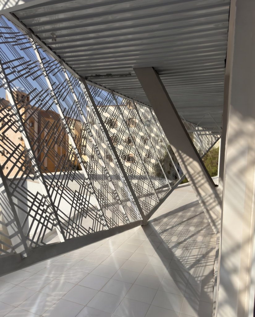 Interior terrace space at the Indonesian Consulate in Jeddah, filtered by light patterns from the Batik metal facade.