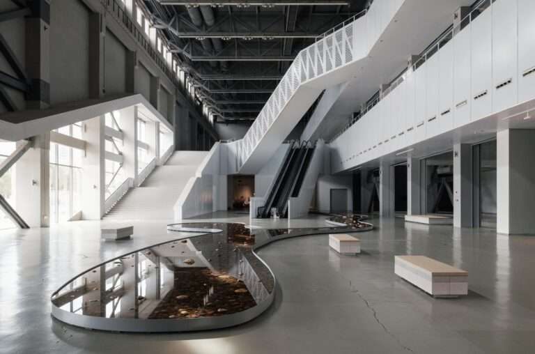 Shallow water installation with stones in a large open museum lobby space.