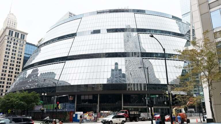 Sloped, reflective glass curtain wall on the curved facade of the Thompson Center undergoing renovation.