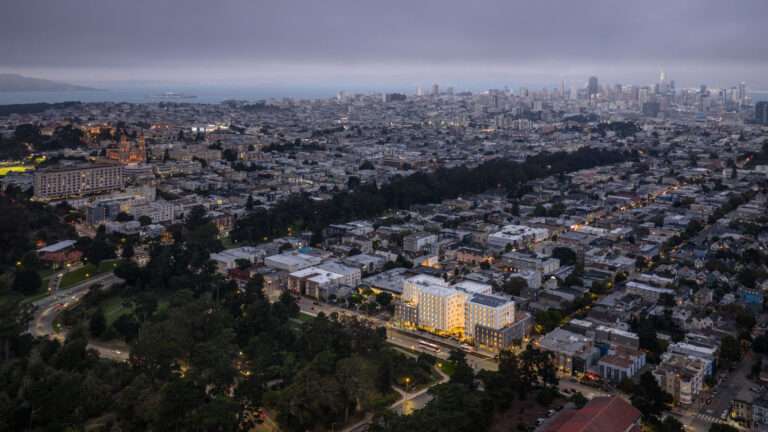 Dusk aerial view showing 730 Stanyan development surrounded by San Francisco urban grid and Golden Gate Park.