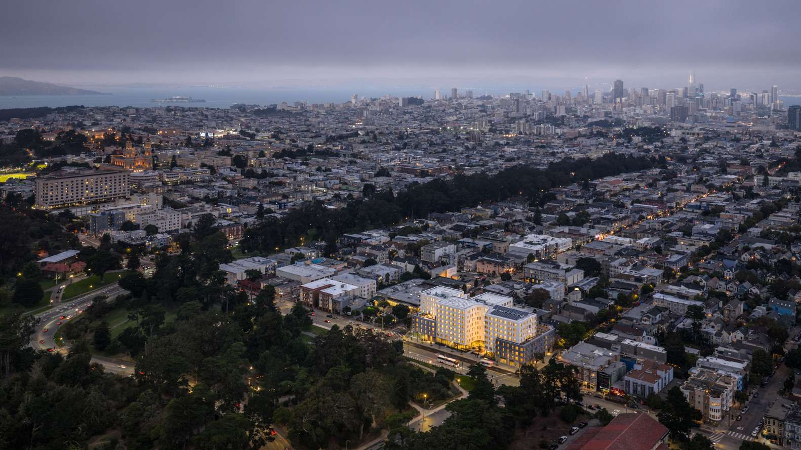 Dusk aerial view showing 730 Stanyan development surrounded by San Francisco urban grid and Golden Gate Park.