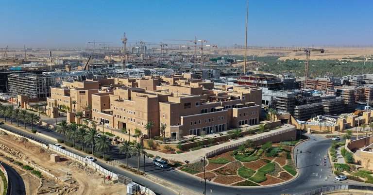 High aerial view of the earthen Ministry of Culture massing amidst surrounding Diriyah construction sites.