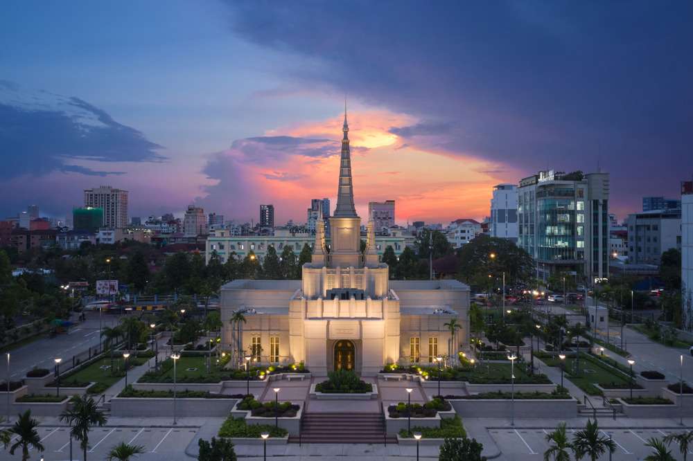 Illuminated temple spire and facade centered behind a terraced plaza at twilight.