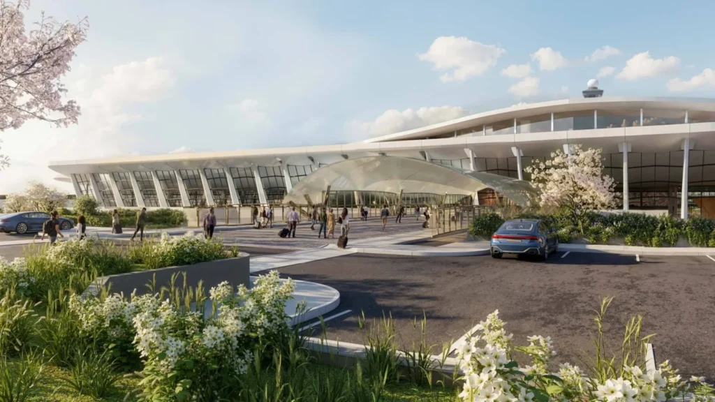 Angled view of curved glass terminal exterior with vehicle drop-off and glass entrance shelter